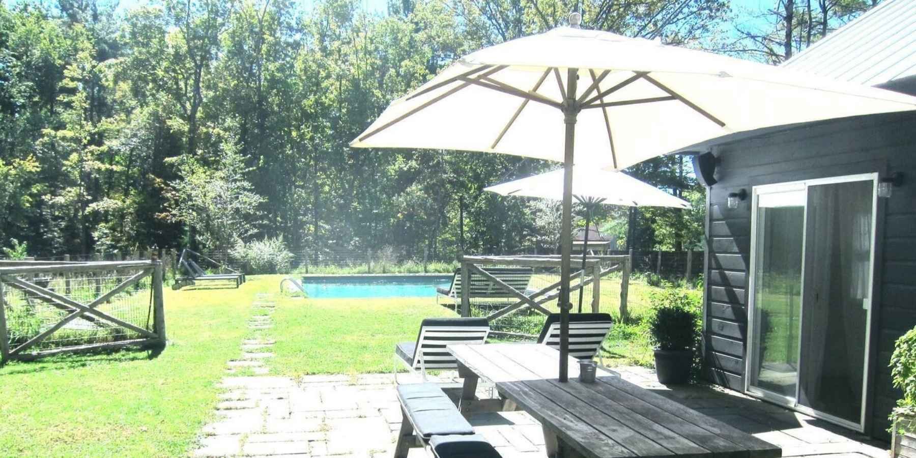 Luxury outdoor patio with umbrella seating overlooking a private backyard pool